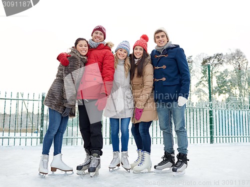 Image of happy friends ice skating on rink outdoors