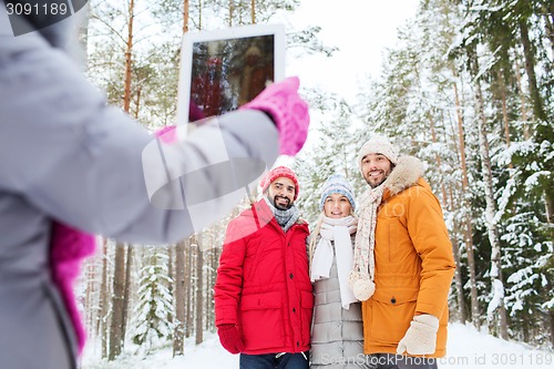 Image of smiling friends with tablet pc in winter forest