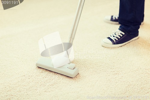 Image of close up of male hoovering carpet