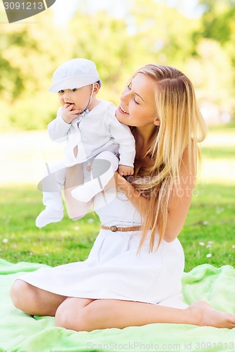 Image of happy mother with little baby sitting on blanket