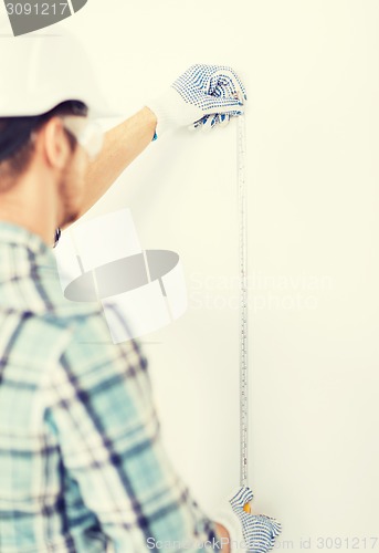 Image of architect measuring wall with flexible ruler