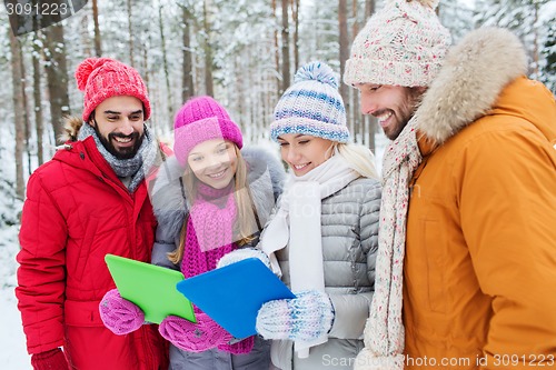 Image of smiling friends with tablet pc in winter forest