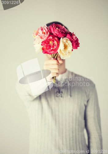 Image of man covering his face with bouquet of flowers
