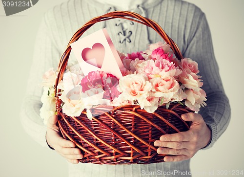 Image of man holding basket full of flowers and postcard