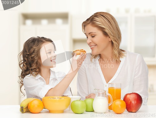 Image of happy mother and daughter eating breakfast