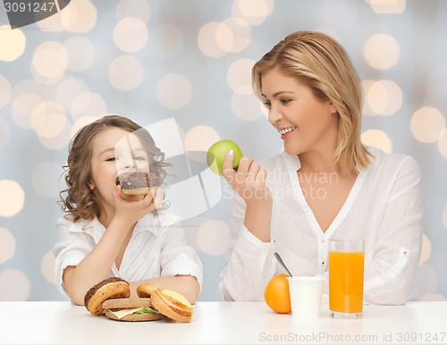 Image of happy mother and daughter eating breakfast