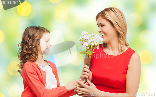 Image of happy little daughter giving flowers to her mother