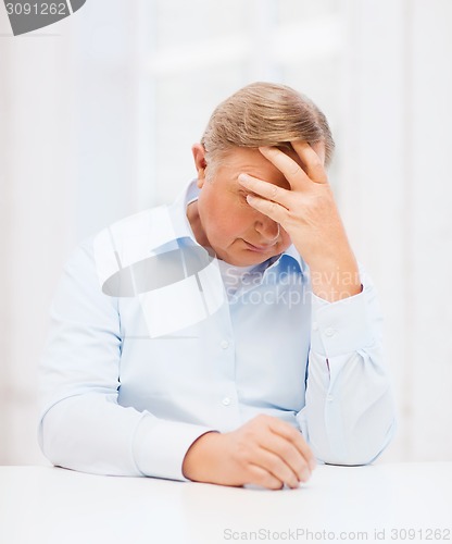 Image of stressed old man holding head at home