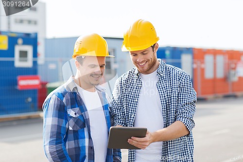 Image of smiling builders in hardhats with tablet pc