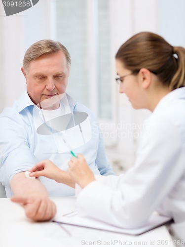 Image of female doctor doing injection to old man