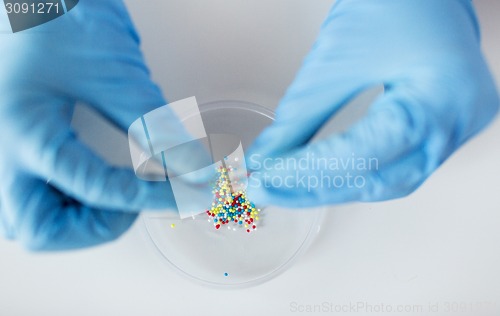 Image of close up of scientist hands holding pill in lab