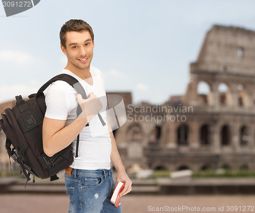 Image of happy young man with backpack and book travelling