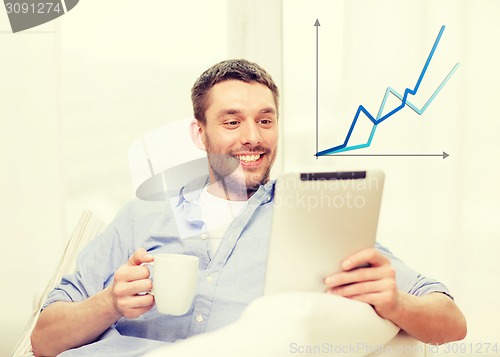 Image of smiling man working with tablet pc at home