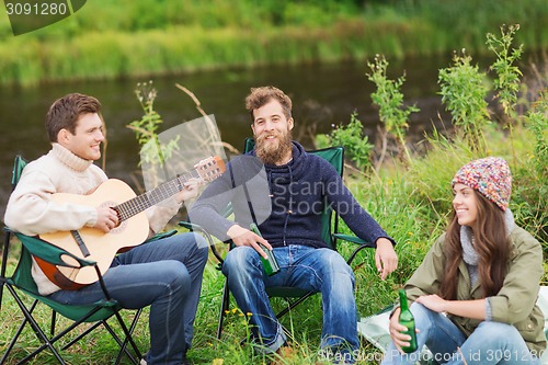 Image of group of tourists playing guitar in camping