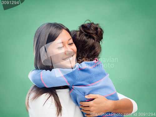 Image of happy woman and little girl hugging at school