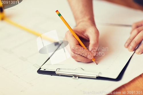 Image of close up of male hands writing in clipboard