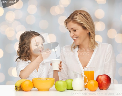 Image of happy mother and daughter eating breakfast