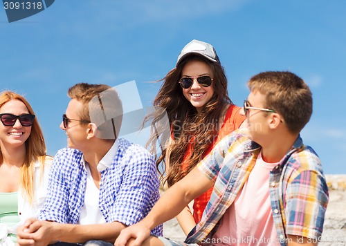 Image of group of smiling friends sitting on city street