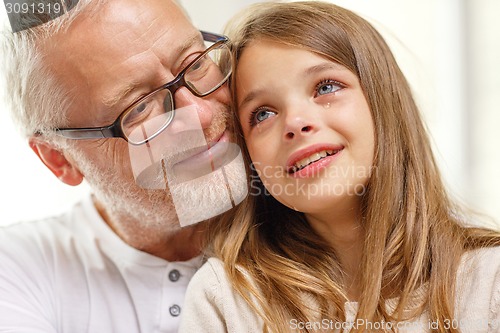 Image of grandfather with crying granddaughter at home