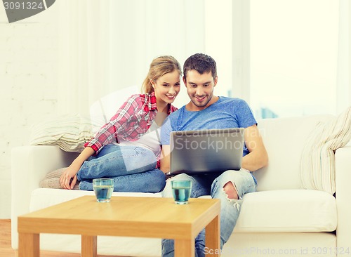 Image of smiling couple with laptop computer at home