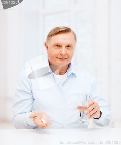 Image of old man with pills ang glass of water