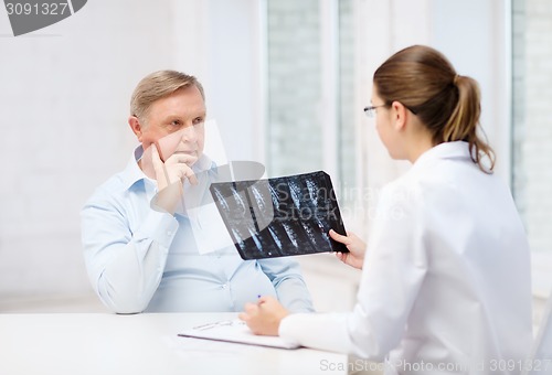 Image of female doctor with old man looking at x-ray
