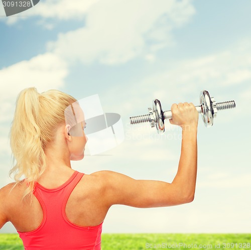 Image of sporty woman with heavy steel dumbbell from back