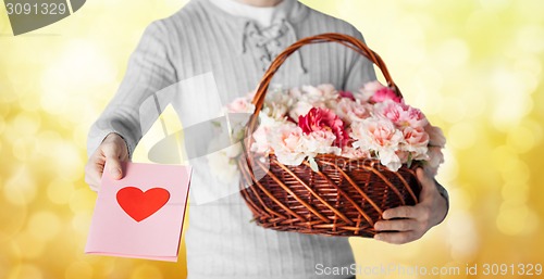 Image of man holding basket full of flowers and postcard