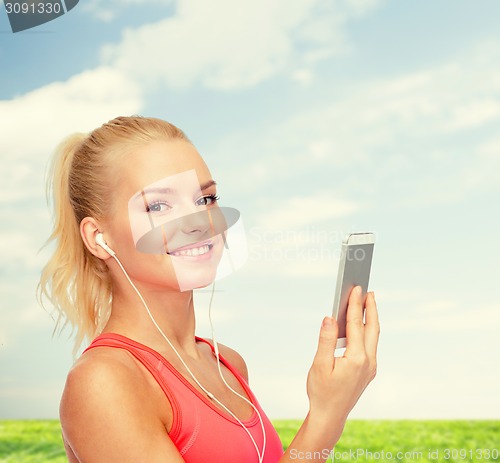 Image of smiling sporty woman with smartphone and earphones