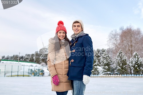 Image of happy couple ice skating on rink outdoors