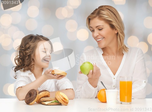 Image of happy mother and daughter eating breakfast