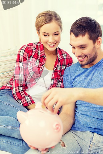 Image of smiling couple with piggybank sitting on sofa