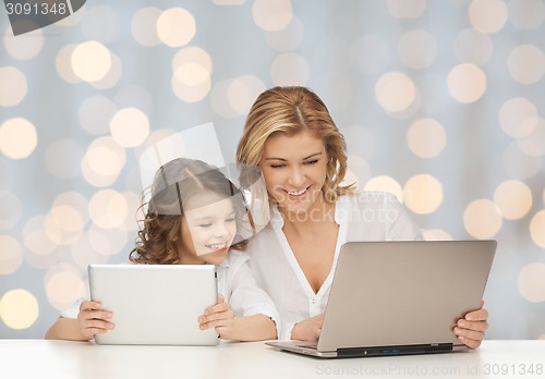 Image of mother with girl looking to laptop and tablet pc