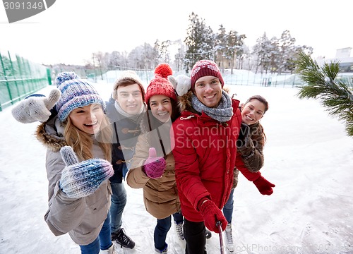 Image of happy friends with smartphone on ice skating rink