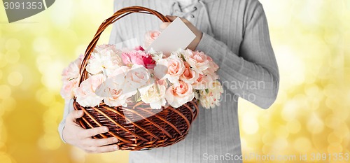 Image of man holding basket full of flowers and postcard