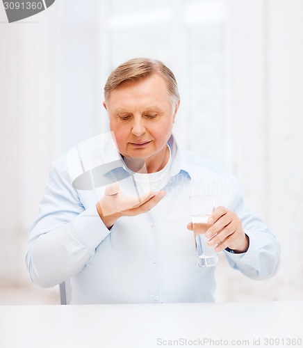 Image of old man with pills ang glass of water