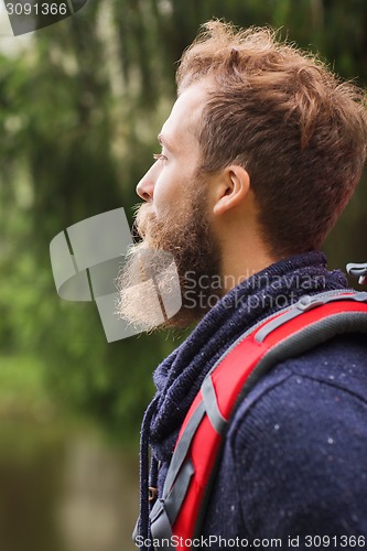 Image of smiling man with beard and backpack hiking