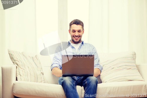 Image of smiling man working with laptop at home