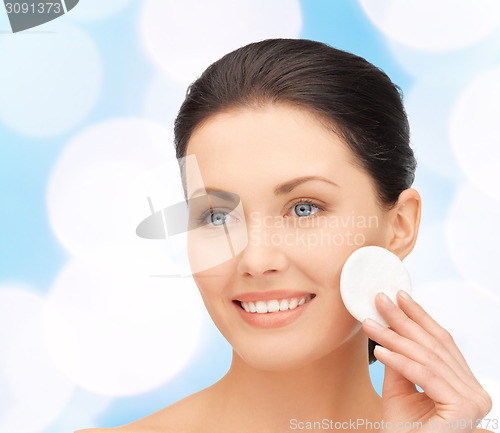 Image of smiling woman cleaning face skin with cotton pad