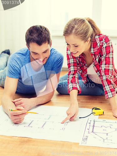 Image of smiling couple looking at blueprint at home