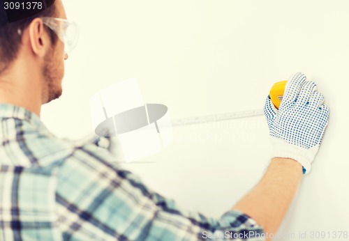 Image of architect measuring wall with flexible ruler