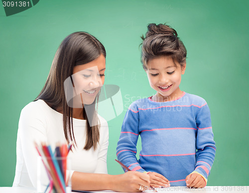 Image of happy teacher and little school girl drawing