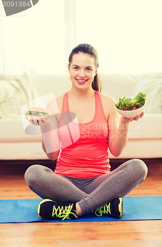 Image of smiling teenager with green salad and hamburger