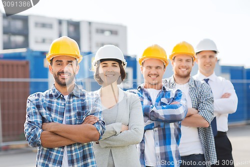 Image of group of smiling builders in hardhats outdoors