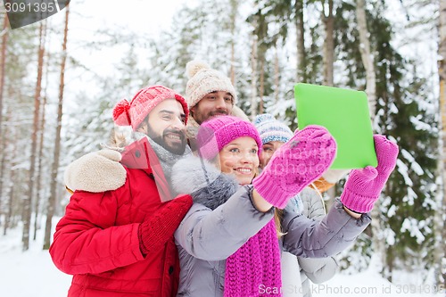 Image of smiling friends with tablet pc in winter forest