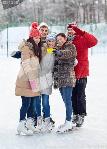 Image of happy friends with smartphone on ice skating rink