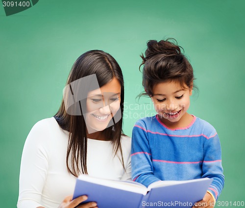 Image of happy teacher and little school girl reading book