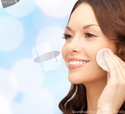 Image of smiling woman cleaning face skin with cotton pad