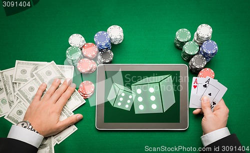 Image of casino poker player with cards, tablet and chips