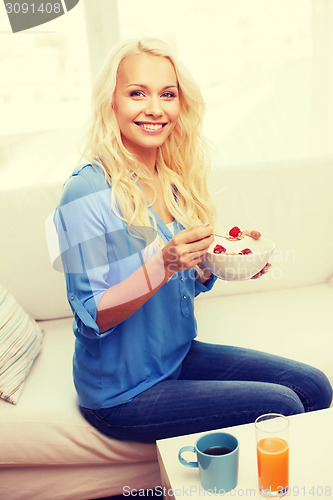 Image of smiling woman with bowl of muesli having breakfast